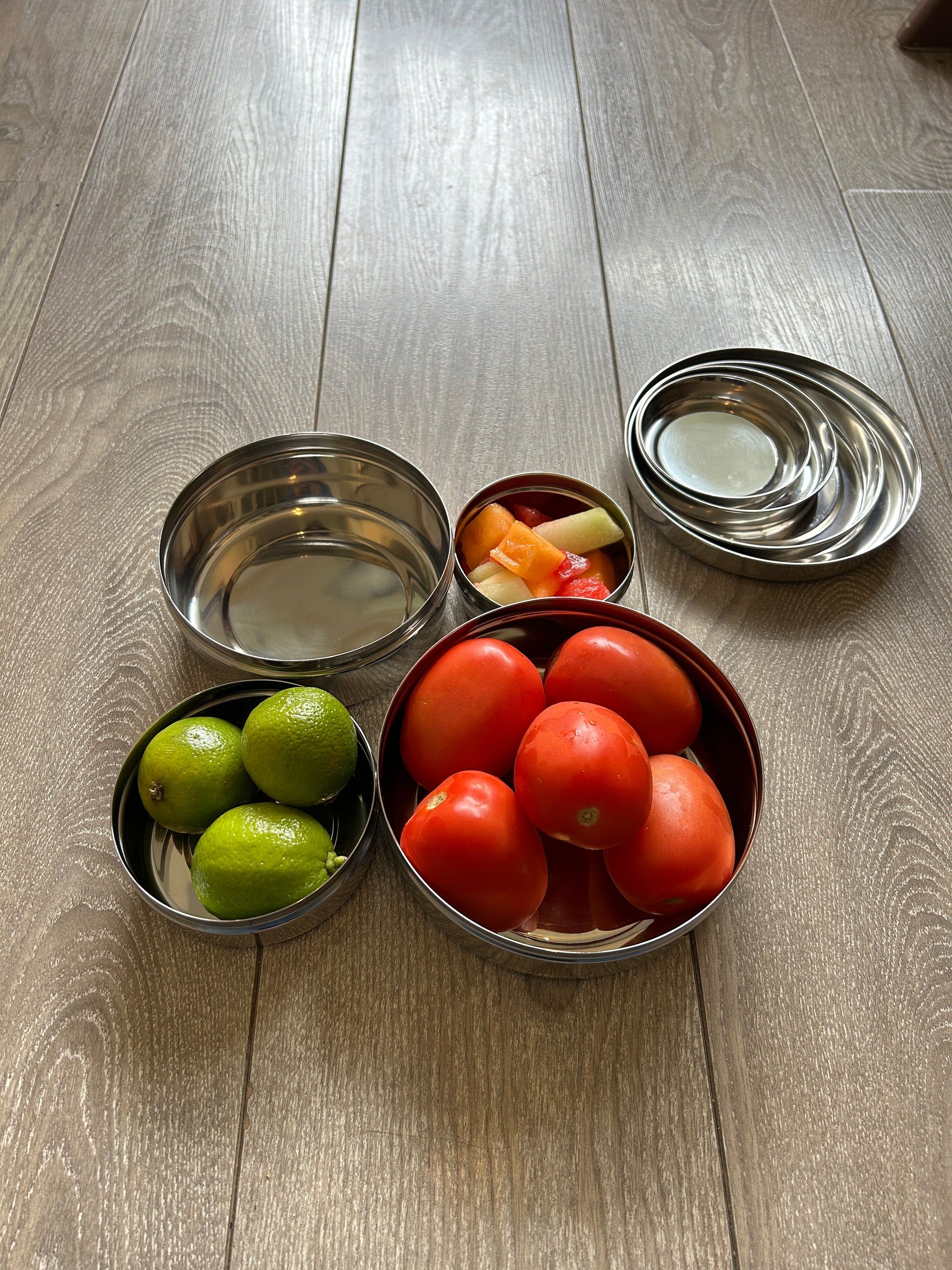 Steel containers with fruits and vegetables on a wooden surface